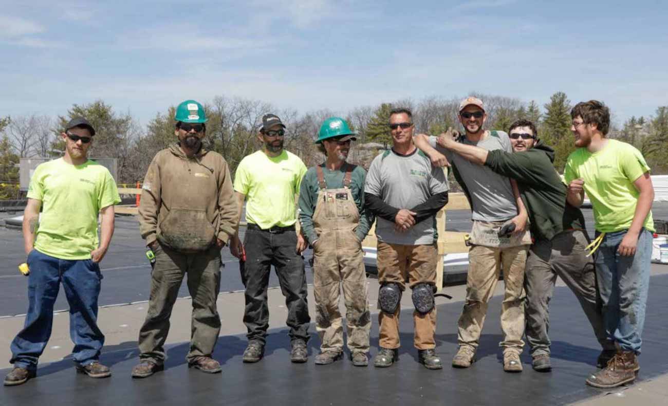 team of commercial roofers posing on a roof