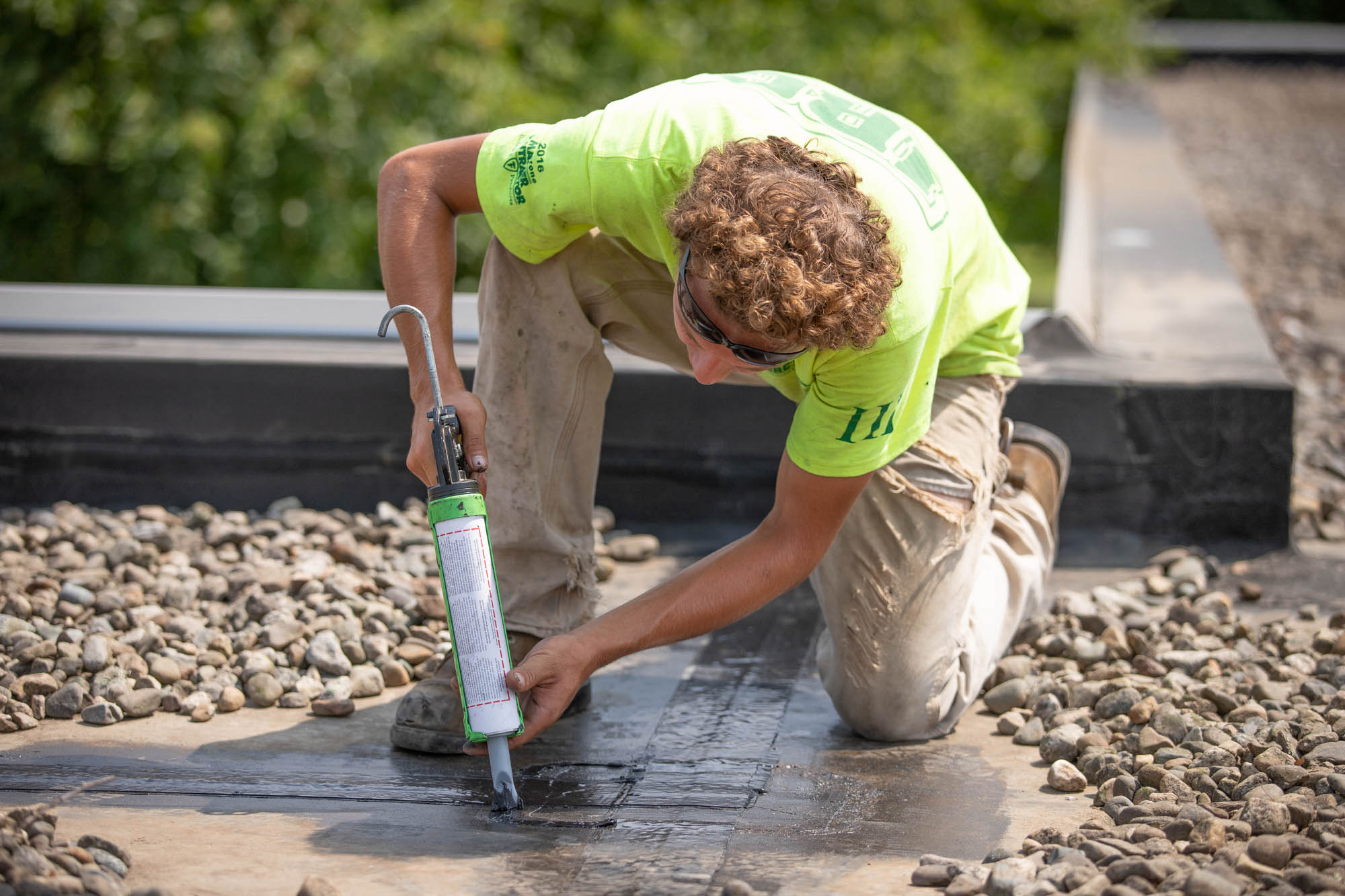 man applying caulking to and stopping leaks on a commercial roof