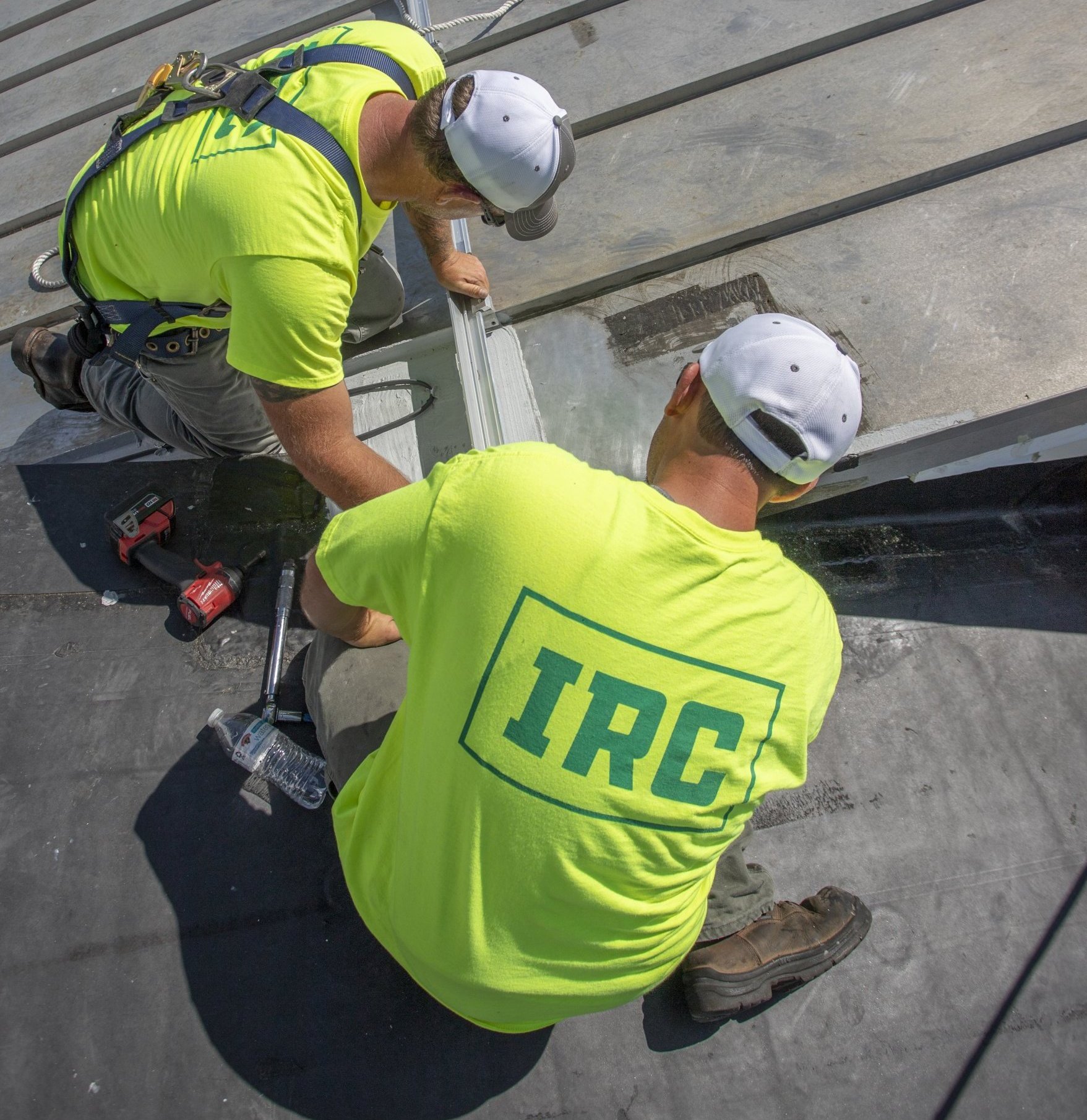 Two roofing technicians installing a new part on a roof