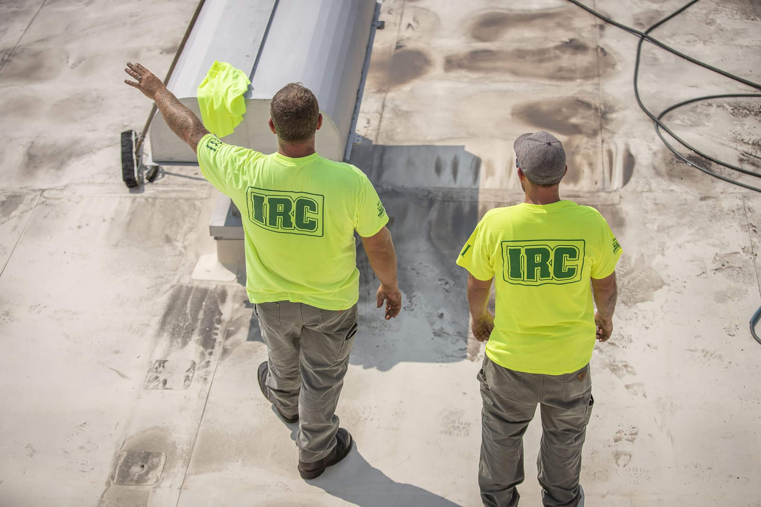 Two roofing technicians standing on a roof, one is directing work
